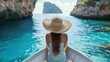 © ProPhotos - A woman sitting on a boat in a calm sea, wearing a straw hat, surrounded by rocks.