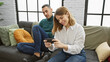 © Krakenimages.com - A woman checks her smartphone next to a man on a couch, portraying modern lifestyle and relationship indoors.