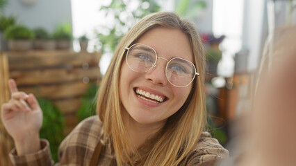 Sticker - Smiling young woman with glasses taking a selfie inside a vibrant flower shop