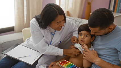 pediatrician examines child with father at home while latino woman doctor smiles, indoor house visit