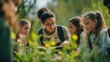 © Athena - A focused young woman guides a group of children in an outdoor learning environment surrounded by vibrant flowers.