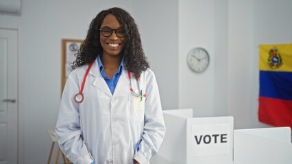 Wall Mural - A beautiful young african american woman with curly hair stands indoors in an electoral college room in venezuela, wearing a lab coat and stethoscope, with a voting booth and flag in the background.