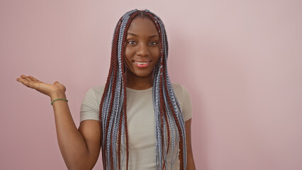 A smiling african american woman with braids presenting against a pink background portrays beauty and confidence.