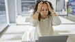 © Krakenimages.com - A stressed hispanic middle-aged woman suffering a headache while working in a bright modern office.
