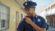 © Krakenimages.com - Portrait of a focused african american male police officer communicating via radio on a city street.