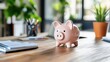 © Pinklife - A pink ceramic piggy bank is set on a wooden desk in a well-lit office environment. The scene embodies financial savings and planning with a touch of optimism and warmth.