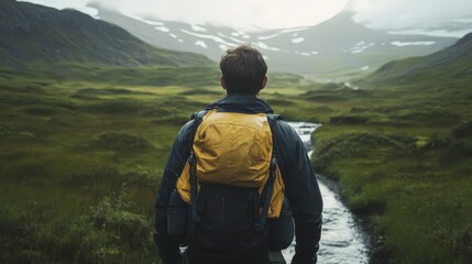 Canvas Print - A man with a backpack stands on a path, looking towards a valley with mountains in the distance, symbolizing adventure, exploration, decision-making, nature, and journey.