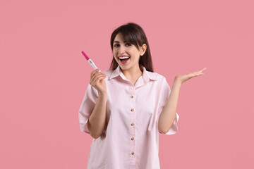 Wall Mural - Happy young woman with pregnancy test on pink background