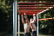 © qunica.com - Two individuals engaging in fitness activities on monkey bars in a park. Focus on fitness, outdoor exercise, and physical strength.