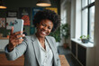 © MOTOKO Stock - Confident African American businesswoman taking selfie in modern office: Ideal for diversity and inclusion campaigns
