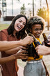 © Xavier Lorenzo - Happy young multiracial friends celebrating and cheering with beer at summer party outdoors. United millennial people laughing having fun together toasting drinks on vacation