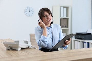 Canvas Print - Professional receptionist working at wooden desk in office