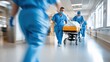 © Pinklife - Medical staff in blue scrubs urgently push a patient on a stretcher through a brightly lit hospital hallway, emphasizing swift emergency medical response.