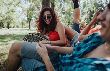 Wall Mural - Group of friends having fun and relaxing at the park under the trees on a sunny day, sharing laughter and good times.