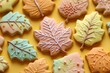 © Khawla - Frosted sugar pastel hues cookies in the shape of autumn leaves, decorated with icing patterns and colors that mimic fall foliage on yellow background