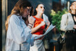 © qunica.com - Young businesswoman deeply engaged in reading documents outdoors, accompanied by her colleagues in a professional setting.