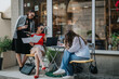 © qunica.com - Three businesswomen having a focused meeting outside a cafe. They are working on documents and a laptop, discussing business strategies and plans.