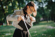 © qunica.com - Young businesswoman searching through her handbag in a park during a sunny day. Concept of work-life balance, fashion, and leisure.