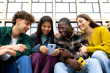 college student friends looking at mobile phone laughing together. group of happy people using smart