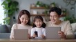 © Stone Story - Happy family using digital devices together at home. Parents and child enjoying technology and spending quality time.