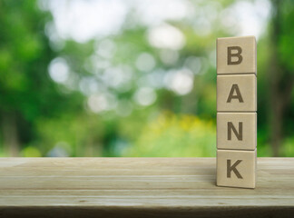 Wall Mural - Bank letter on wood block cubes on wooden table over blur green tree in park, Business banking service concept