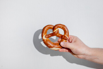 A hand holding a soft pretzel against a plain background, perfect for Oktoberfest celebration imagery