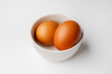 Two brown eggs in a white bowl, representing simplicity and Easter holiday traditions