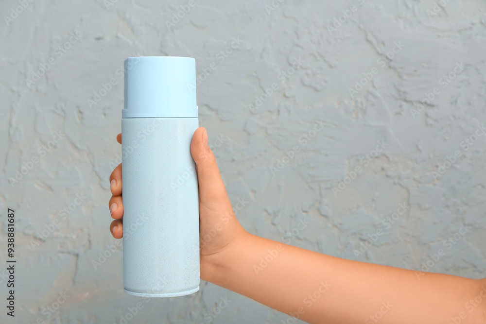 Female hand with spray paint can against color wall, closeup