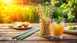 © Four888 - Colorful striped paper straw lies on a natural wood table surrounded by summer vibes, refreshing drinks, and a warm sunny day atmosphere.