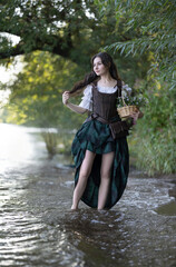 Wall Mural - A girl in a corset and skirt walks along the riverbank