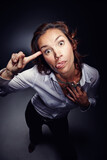 Mocking, tongue out and face of woman with rude gesture isolated on dark background in studio. Funny, mean and portrait of person gesturing for talking, conversation and backchat communication