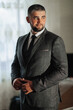 © Vasil - A man in a suit and tie stands in front of a window. He is smiling and he is confident