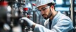 © raja - A worker in a white coat and hard hat inspecting industrial machinery