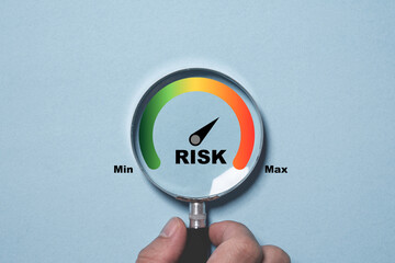 hand holding magnifier glass with risk level indicator rating since low to high on blue background f