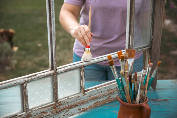 Painting a wooden vintage window outdoors, an eco-friendly re-use business.