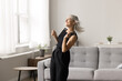 © fizkes - Carefree mature blonde woman in casual clothes spend pastime at home listening favourite track moving to cool popular music looks untroubled, dancing, enjoy weekend alone in fashionable living room