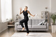 © fizkes - Lively woman jumping, having fun, dancing at modern own apartment, move to music in cozy living room on weekend, feeling joyful, carefree and energized, enjoy happy moments alone at home. Recreation
