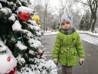 new year, christmas, child stands by new year tree, snowman, holidays, childhood, boy in green jacket, snow, winter