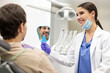 © Home-stock - Positive man checking results of teeth whitening treatment in the dentist's office. Woman dentist holding mirror to satisfied male patient