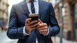 © Baramee - A business man in a suit is looking at his phone. He is wearing a tie and he is focused on his phone