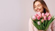 © Hordina Anastasia  - beautiful young woman laughs, holds a bouquet of tulips in her hands, spring holiday, mother, congratulation, gift, flowers, place for text, just like that, surprise, joy, relationship