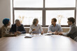 © fizkes - Five young and mature multiethnic staff engaged in briefing at conference table. Shareholders review company financial statement, analyzing profits, losses, revenue, discussing dividend and policies