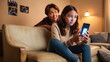 © Borneo - Parental monitoring of teens. Curious mother spying daughter, girl messaging on smartphone on sofa at home