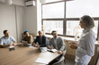 © fizkes - Middle-aged businesswoman leading formal corporate meeting for staff, hold negotiations with shareholders, make speech standing in front of partners. Strategy planning, opinion exchange, leadership