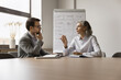 © fizkes - Two professionals met in conference room engaged in business-related discussion, mature female explaining or emphasizing point, while man listening attentively. Strategizing, problem solutions search