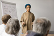 © fizkes - Young 30s African businesswoman, company executive, corporate staff member hold workshop for managers, team leaders, and stakeholders involved in strategic planning and decision-making. Training event