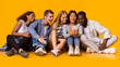 © Prostock-studio - Group of multiracial cheerful classmates having break, watching videos on smartphone over yellow background, panorama