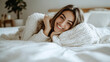 © alphaonetwo - Smiling woman lying in a white blanket on a white bed