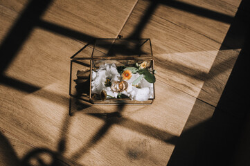 Wedding photography, top view of set, accessories, details, top view of glass box with flowers, silver rings in hotel room in sunlight.