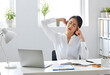 © MRSUTIN - Stressed Asian businesswoman sitting at desk with eyes closed and temples rubbing to show fatigue.